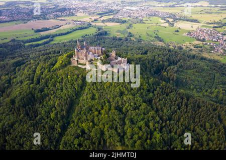 Drone shot of Hohenzollern Castle on forested mountain top in the Swabian Alps in summer. Scenic aerial view of old German Burg. Famous fairytale Gothic landmark in Stuttgart vicinity Stock Photo