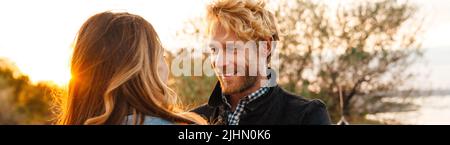 White mid couple smiling and looking at each other while standing outdoors Stock Photo