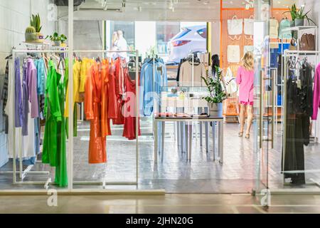 Colorful clothes on hangers, assortment in light clothing store, season shopping. Fashion choice of clothes in bright colors Stock Photo