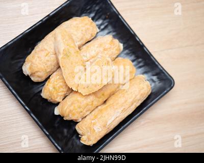 Stack of shrimp egg rolls on a black square bowl. Shoot on a wooden table Stock Photo