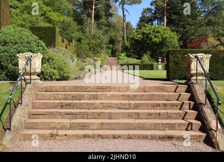 Old stone steps lead up to a gravel path and onwards to a second set of steps in the grounds of an English country house Stock Photo