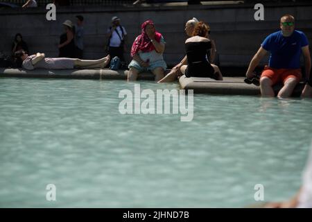 London, Britain. 19th July, 2022. People sit by a fountain in London, Britain, on July 19, 2022. The United Kingdom (UK) had its hottest day on record on Tuesday with temperatures exceeding 40 degrees Celsius in some places. Credit: Tim Ireland/Xinhua/Alamy Live News Stock Photo