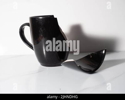 Broken black porcelain coffee cup on a white background Stock Photo