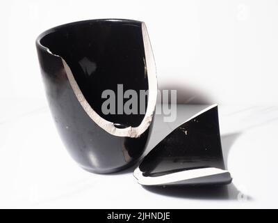 Broken black porcelain coffee cup on a white background Stock Photo