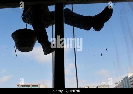 Rappeling man work on external window cleaning service and building repair. Workman rappel renovating building. Carpenter construction worker Stock Photo