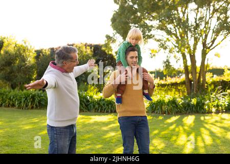 Image of happy three generation caucasian men walking in garden Stock Photo