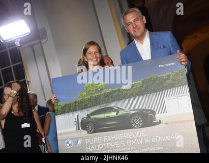 19 July 2022, Bavaria, Oberschleißheim: The winner of the main prize of the Sternstunden raffle, Kathrin Krupka (l), shows off with Stefan Teuchert, Head of Sales at BMW Germany, at the summer reception of the Bavarian Parliament at Schleißheim Castle. Photo: Felix Hörhager/dpa Stock Photo