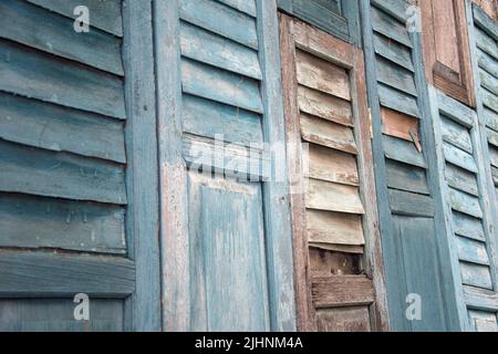 Wooden blue closed shutters on the window of an old traditional village house. Stock Photo