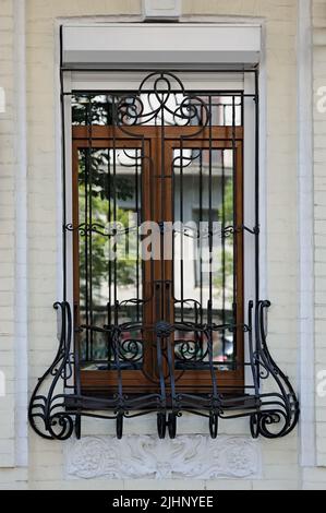 Iron lattice on window with white bas relief beneath in Kyiv Ukraine Stock Photo