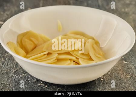 Potato chips in white plate ready for potato and sweet potato gratin Stock Photo