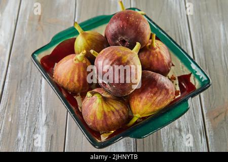 Fresh figs In green plate on wooden background Stock Photo
