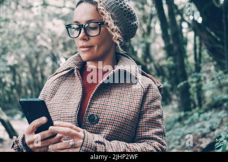 Portrait of cute trendy woman using modern mobile phone app gadget. Independent lady use cellular smiling and enjoying connection. Concept of people a Stock Photo