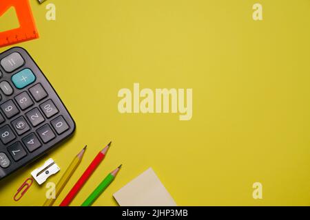 Calculator and stationery in different colors on a yellow background with copy space Stock Photo