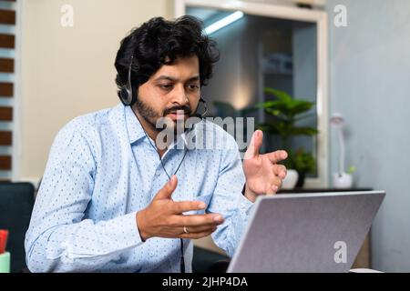 Corporate employee busy attanding meeting by advising on laptop at office - concept of customer service, client support and communication skills. Stock Photo