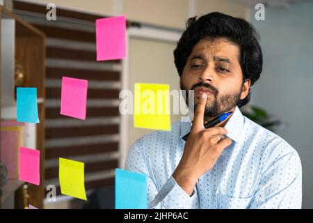 thoughtful young entrepreneur busy planning while working at office - concept of making business strategy, brainstorming and analysis Stock Photo