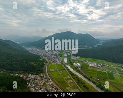 Aerial view of river flowing through small town in valley Stock Photo