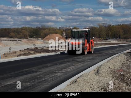 Roller rolling fresh hot asphalt on the new road. Road construction. Stock Photo