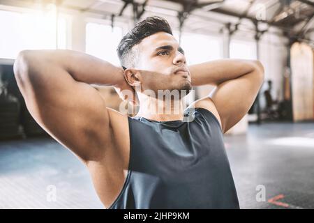 Focused athlete doing sit ups in the gym. Bodybuilder working on his abs and core in the gym. Young serious trainer doing his exercise routine in the Stock Photo