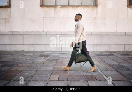 Black businessman travelling alone.A african american businessman walking around town with his luggage while looking stylish in the city Stock Photo