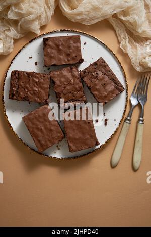 Delicious homemade chocolate brownies served on white plate over beige background Stock Photo