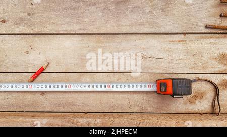 Tape measure and pencil on a wooden workbench. Textured wooden table with tools and copy space on the table Stock Photo