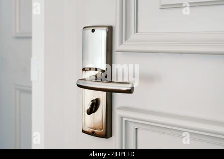 Hotel apartment door, white wooden doorway with metal handle, selective focus Stock Photo