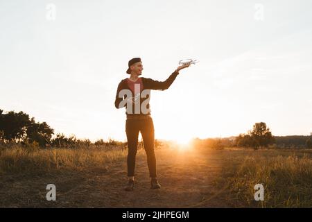 Young man standing with drone outdoor, sunset Stock Photo