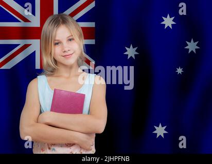 School student girl standing with book on Australian flag background. Education and school in Australia concept. Stock Photo