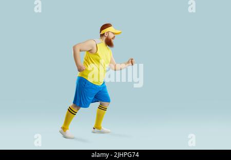 Funny fat man having weight loss workout and running isolated on blue background Stock Photo