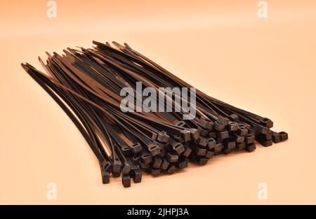 Black cable ties isolated on orange background. Plastic Tie Wraps. Stock Photo