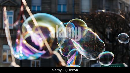 Multiple balloon bubble made from soap - flying above the city with apartment building in background - concept for real estate bubble Stock Photo