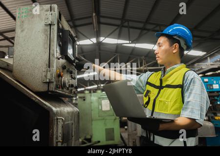 Asian engineer working on laptop and check engine in industry Stock Photo