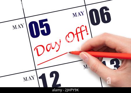 5th day of May. Hand writing text DAY OFF and drawing a line on calendar date 5 May. Vacation planning concept. Spring month, day of the year concept. Stock Photo