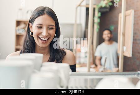 One happy hispanic waitress using a coffee machine to prepare a hot beverage in a cafe. Happy barista making a warm drink to serve customers in a Stock Photo