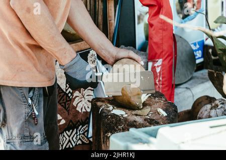 A man cutting a coconut to get fresh coconut milk in Hawaii while on vacation Stock Photo