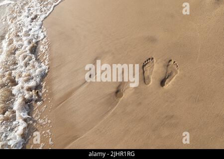 Two sets of footprints in the sand on a walk in Maui Hawaii Stock Photo