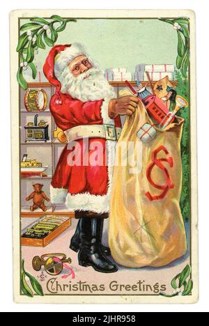 Original Edwardian era Christmas postcard of Santa with sack of toys, loading presents from his store shelves, circa 1907, U.K. Stock Photo