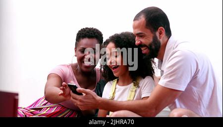 Multi-ethnic family using cellphone. Interracial parents and mixed race children looking at smartphone screen together Stock Photo