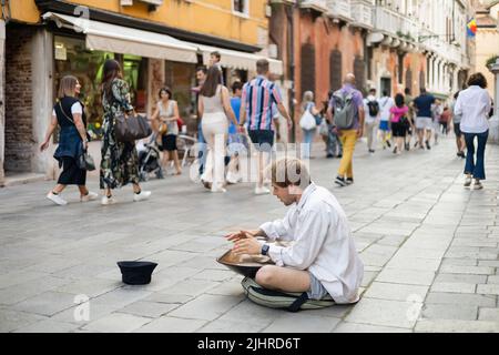 VENICE, ITALY - MAY 22, 2022: Street musician playing hang near hat on urban street Stock Photo