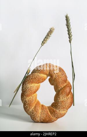 Fresh bread loaf on white table. Baked bread and ears of wheat still life. Stock Photo