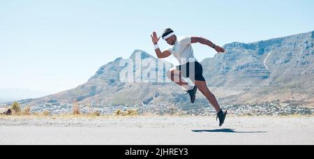 A fit handsome mixed race handsome young man wearing sunglasses running alone outside during the day. Indian male exercising outside during a run in Stock Photo