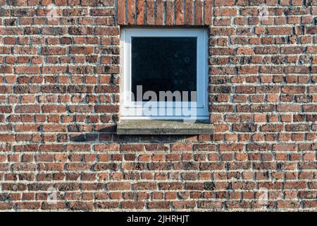 Small window in the middle of a red brick wall Stock Photo