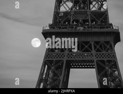 A grayscale shot of the Eiffel tower with the full moon in the background, Paris, France Stock Photo