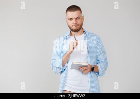 handsome man in blue shirt writing note in notebook Stock Photo