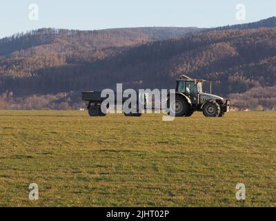 BIELSKO-BIALA, POLAND on APRIL 2020: Tractor and trailer on grassy airfield in european city, clear blue sky in warm sunny spring day. Stock Photo