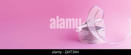 Festive elegant beautiful gift wrapping ribbon isolated on pink background, front view. Celebration banner for website. Stock Photo