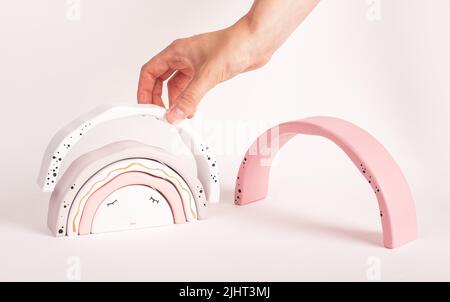 Woman putting arcs together in rainbow stacker. Wooden toy for kids for imagination, motor skills, sense of comparison development. High quality photo Stock Photo