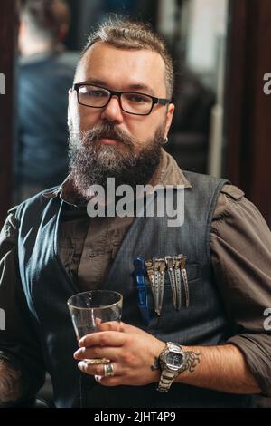 Brutal biker looking at camera with whiskey Stock Photo
