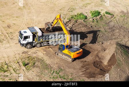 Industrial truck loader excavator moving earth and unloading into a dumper truck Stock Photo