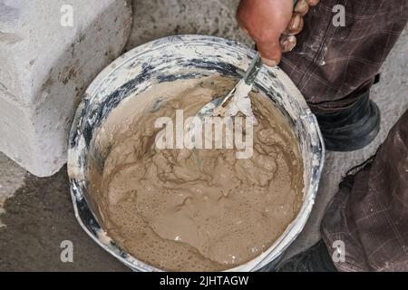 Wet mortar cement paste mixed in bucket, closeup detail from above Stock Photo